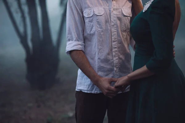 Loving couple in a foggy forest, they hold hands — Stock Photo, Image