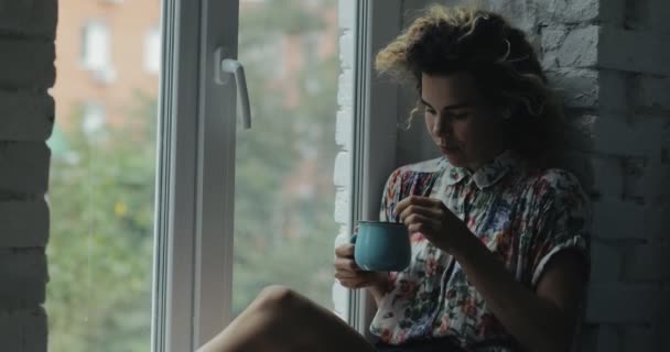 女性がウィンドウでお茶を楽しむ — ストック動画