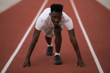 Afrika kökenli Amerikalı erkek sporcu stadyum pistinde koşmaya hazır.