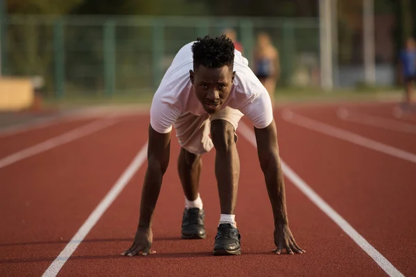 African american male sportsman ready to run on stadium track, sprint run from low start — Stock Photo, Image
