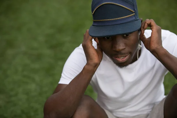Афро-американських чоловічих спортсмен, сидячи на траві і слухати музику в навушники — стокове фото