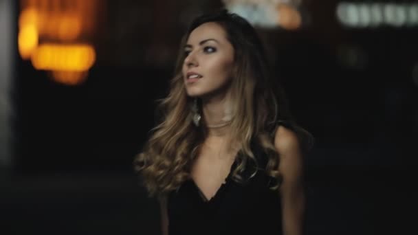 Modelo de moda con hermoso cabello caminando en una calle nocturna de la ciudad — Vídeo de stock