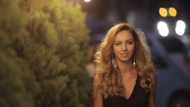 Jolie femme aux beaux cheveux marchant dans une rue de la ville du soir, au ralenti — Video