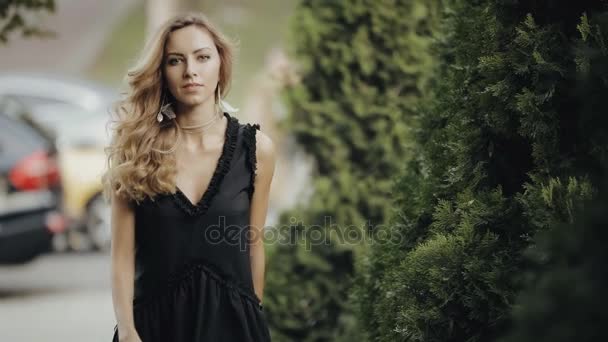 Hermosa mujer con el pelo rizado y pendientes caminando en el parque verde de la ciudad, slow motion — Vídeo de stock