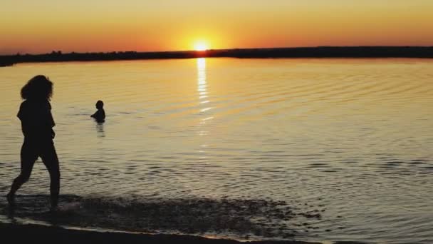 Silhouette of happy woman runs around river at sunset in slow motion — Stock Video