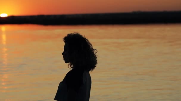 Kunst silhouet van de vrouw gezicht tegen de achtergrond van de rivier bij Rode zonsondergang in slow motion — Stockvideo