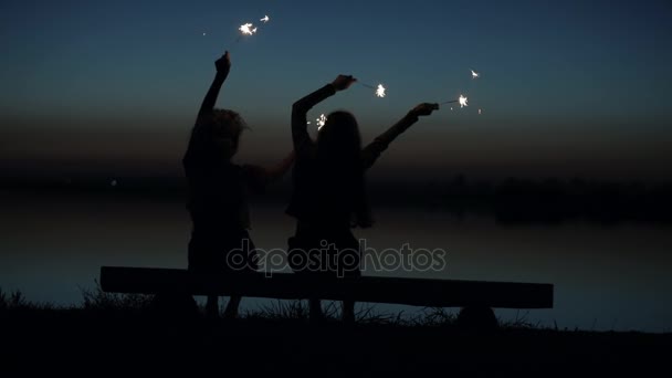 Zwei Freundinnen amüsieren sich mit Wunderkerzen am Fluss, Rückseite — Stockvideo