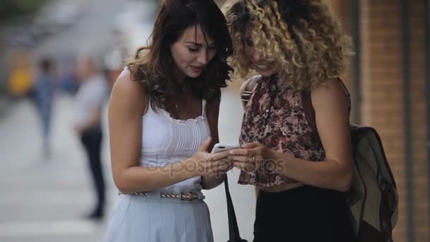 Щасливі друзі жінок дивиться фотографії в смартфоні та гіґґінгу — стокове відео
