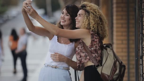 Happy two women friends make selfie pictures by smartphone in city street, slowmotion — Stock Video
