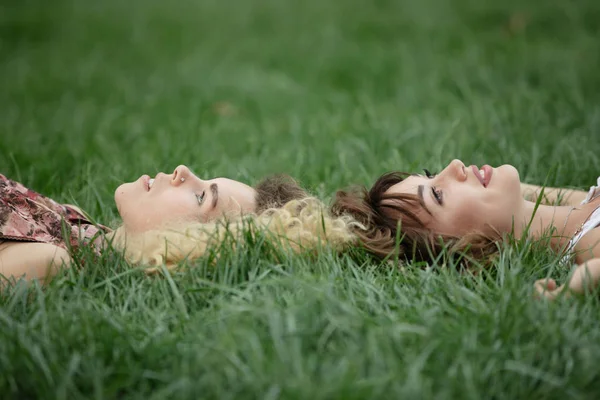 To kvinner lå og hvilte på et gress. – stockfoto
