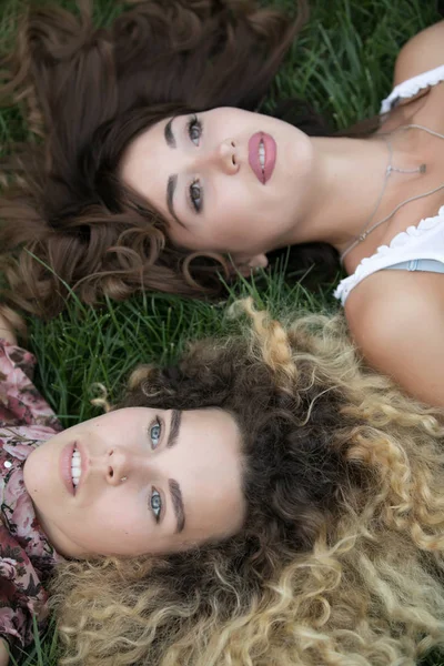 Dos mujeres yacen y descansan sobre una hierba — Foto de Stock