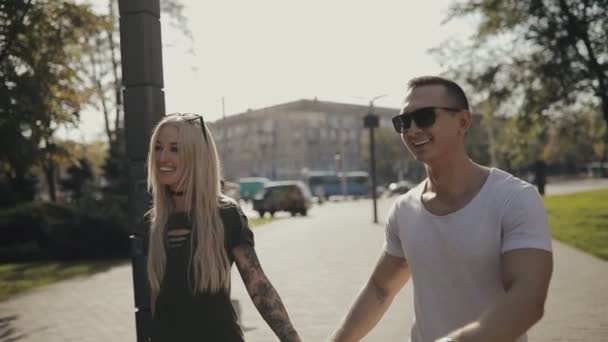 Счастливая молодая пара, идущая вместе по городской аллее, держась за руки — стоковое видео