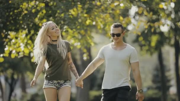 Gelukkige jonge paar lopen samen op stadspark hand in hand — Stockvideo