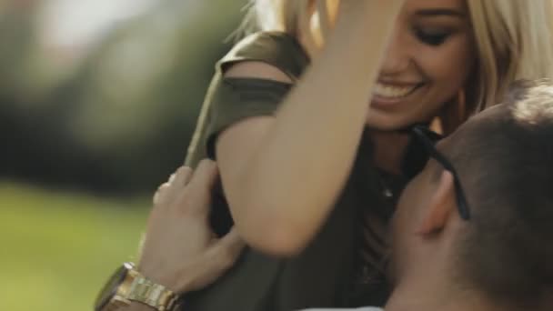 Feliz joven pareja sentada en la hierba en el parque y divertirse, slow motion — Vídeos de Stock