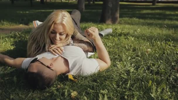Gelukkige jonge paar liggen op gras in park en plezier, slowmotion — Stockvideo