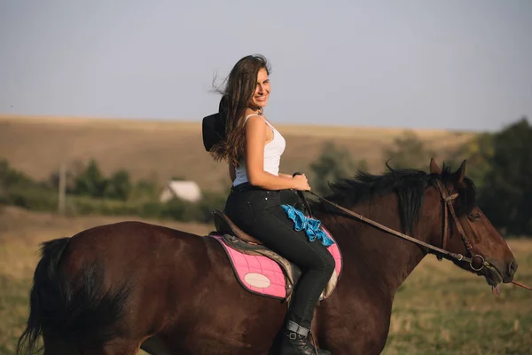 Vackra unga cowgirl ridning hennes häst i fältet — Stockfoto