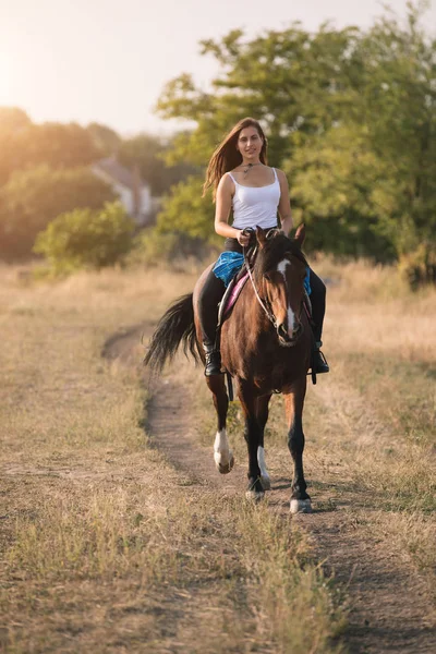 Schöne junge Cowgirl reitet ihr Pferd in Feld — Stockfoto