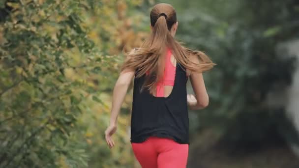 Deportiva corriendo al aire libre en un desgaste deportivo en el día nublado de otoño, cámara lenta — Vídeos de Stock