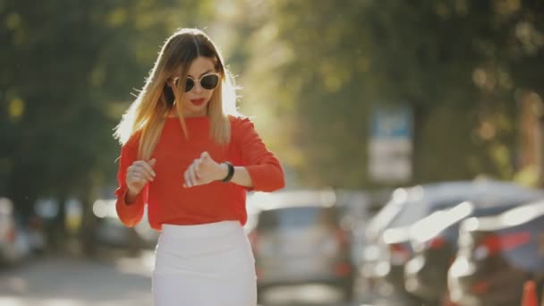 Young pretty business woman looking time at watch walking in city street — Stock Video