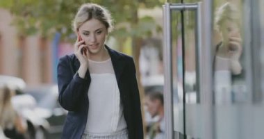 Genç kadın öğrenci şehirde akıllı telefonla konuşurken Klasik takım elbise