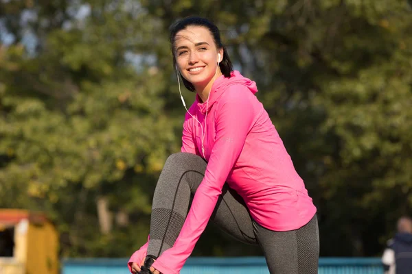 Giovane donna sorridente in rosa cinturino sportivo lacci da scarpe sul ponte all'aperto — Foto Stock