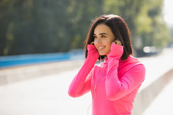 Lachend portret van de jonge vrouw in roze sportkleding klaar om te joggen buiten — Stockfoto
