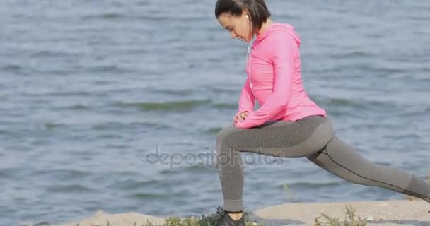 Pretty vigorous sportswoman in pink sportswear warming up before workout outdoors, healthy lifestyle concept — Stock Video