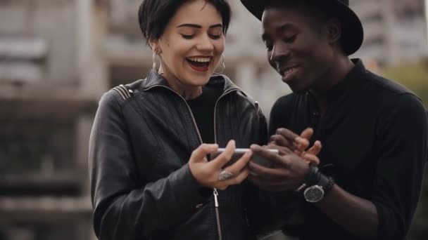 Rallentamento della donna bianca e coppia di uomini neri guardando verso il basso per il video su smartphone. Ridono insieme, il video è molto ridicolo . — Video Stock