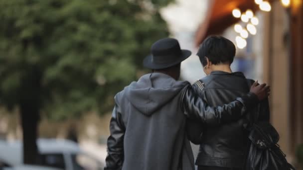 Slowmotion běloška a černoch chodit společně. On ji objal v městské ulici, zadní. — Stock video