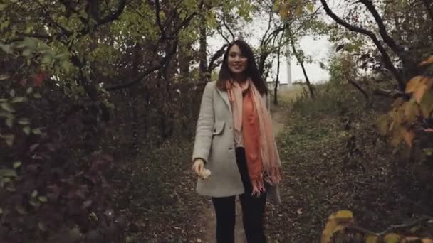 Счастливая и веселая женщина наслаждаясь осенью, она ходит по природе между желтыми деревьями, медленное движение — стоковое видео