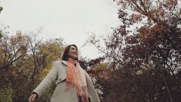 Mujer feliz y alegre disfrutando del otoño, levanta las manos y gira en el bosque, cámara lenta — Vídeo de stock