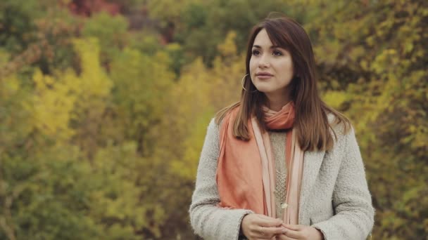 Щаслива молода усміхнена жінка портрет в осінній день на фоні жовтого листя, повільний рух — стокове відео