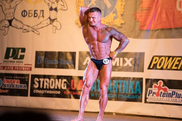 Ukrayna, Dnepr - 08 Ekim 2017: Vücut geliştirme Yarışması show. Açılan Şampiyonası. Güçlü musculars sporcu adam bir sahnede poz.
