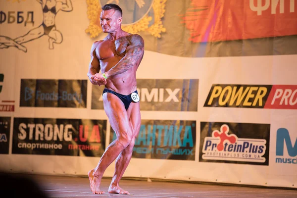 Oekraïne, Dnepr - 08 oktober 2017: Bodybuilding competitie show. Geopende kampioenschap. Sterke spieren atleet man poseren op een podium. — Stockfoto