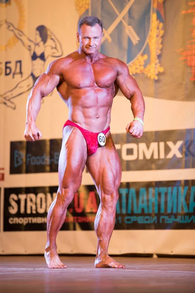 Ukrayna, Dnepr - 08 Ekim 2017: Vücut geliştirme Yarışması show. Açılan Şampiyonası. Güçlü musculars sporcu adam bir sahnede poz.