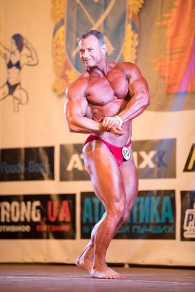 Ukraine, dnepr - 08. Oktober 2017: Bodybuilding-Wettkampfshow. Meisterschaft eröffnet. kräftiger muskulöser Athlet posiert auf einer Bühne. — Stockfoto