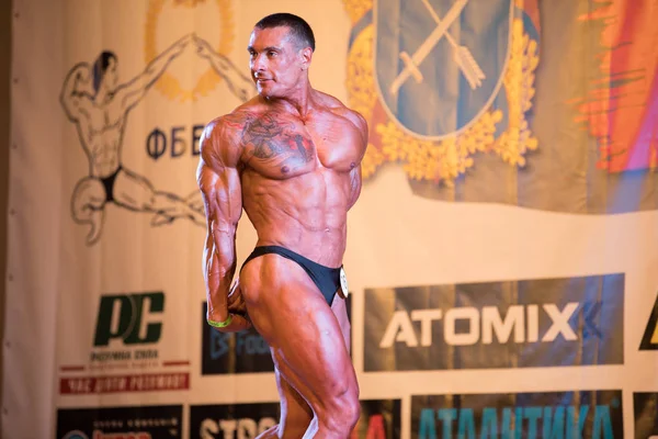 Ukrayna, Dnepr - 08 Ekim 2017: Vücut geliştirme Yarışması show. Açılan Şampiyonası. Güçlü musculars sporcu adam bir sahnede poz.