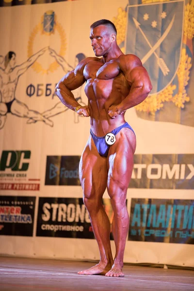 Ukraine, dnepr - 08. Oktober 2017: Bodybuilding-Wettkampfshow. Meisterschaft eröffnet. kräftiger muskulöser Athlet posiert auf einer Bühne. — Stockfoto