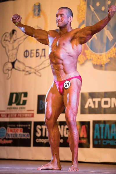 Ukrayna, Dnepr - 08 Ekim 2017: Vücut geliştirme Yarışması show. Açılan Şampiyonası. Güçlü musculars sporcu adam bir sahnede poz. — Stok fotoğraf
