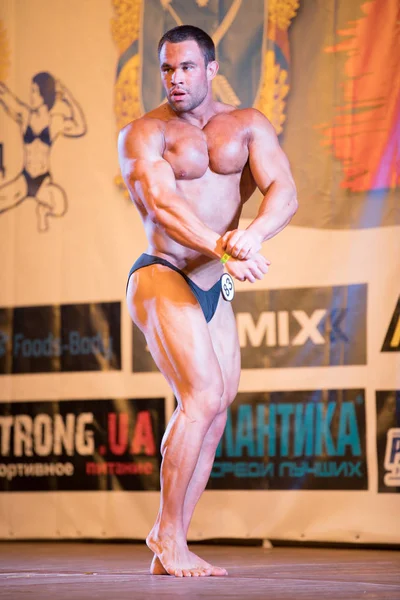 UKRAINE, DNEPR - OCTOBER 08, 2017: Bodybuilding competition show. Opened championship. Strong musculars athlete man posing on a stage. — Stock Photo, Image