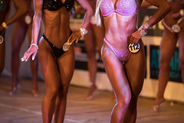 UCRANIA, DNEPR - 08 DE OCTUBRE DE 2017: Miss concurso de bikini fitness. Campeonato abierto. Musculares fuertes atletas mujeres posando en un escenario. Disparo recortado . —  Fotos de Stock