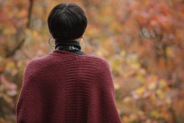 Arka plan üzerinde marsala renk hırka sonbahar orman, bulanık sarı yapraklar içinde tanınmayan sıradışı kadın arkadan görünüş