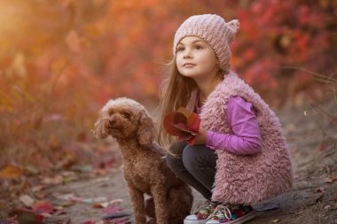 Küçük kız köpekle birlikte doğa üzerinde oturan sonbahar günü, sanat portre