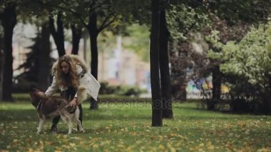 Kadın parkta husky köpek ile sonbahar gününde oynarken yavaş hareket