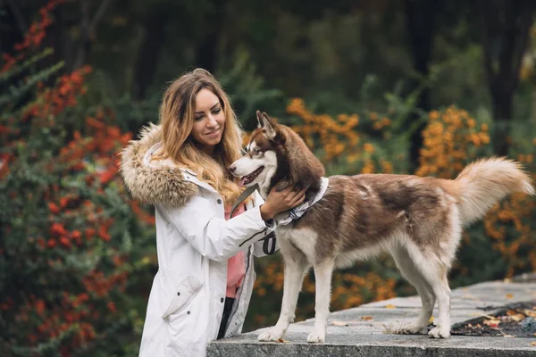 Retrato de mulher com seu cão husky no parque no dia de outono — Fotografia de Stock