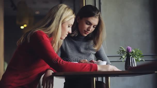 Друзі жінки дивляться щось смішне в смартфоні в кафе — стокове відео