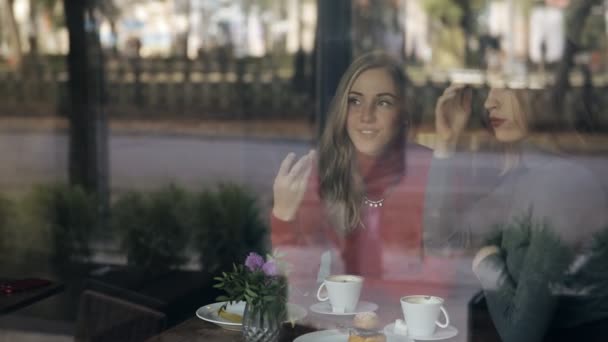Женщины-друзья отдыхают в кафе, разговаривают и улыбаются, смотрят в окно — стоковое видео