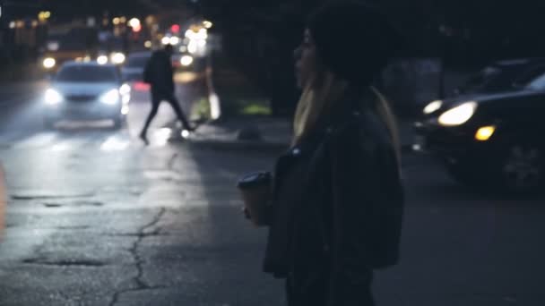 Mujer sola lista para cruzar una calle, ciudad luces noche — Vídeo de stock