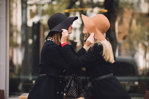 Las amigas a la moda en el sombrero hacen el gesto del beso uno a otro —  Fotos de Stock