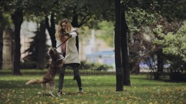 Kadın parkta husky köpek ile sonbahar gününde oynarken yavaş hareket